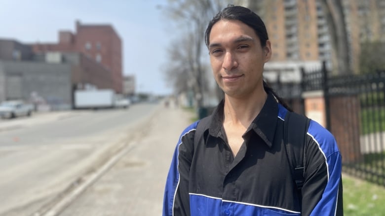 A man standing outside wearing a blue and black jacket.