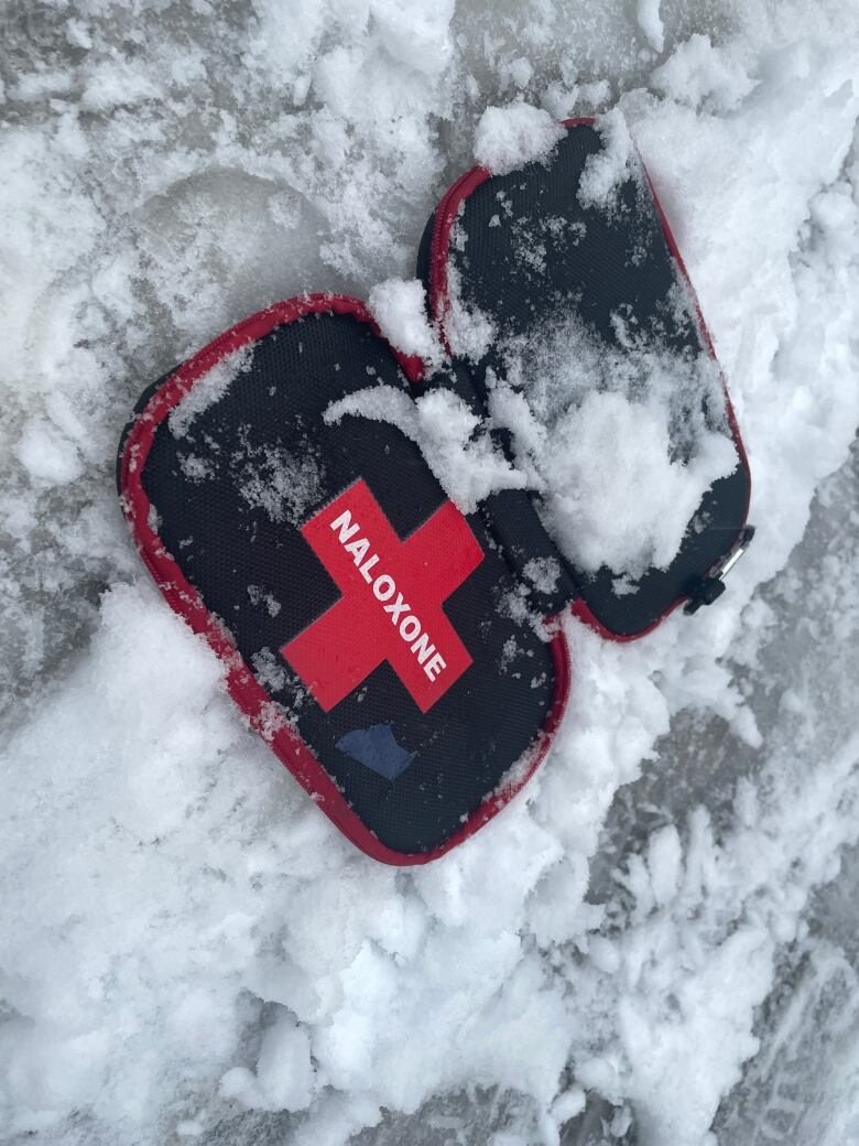 A black and red naloxone kit in some snow.