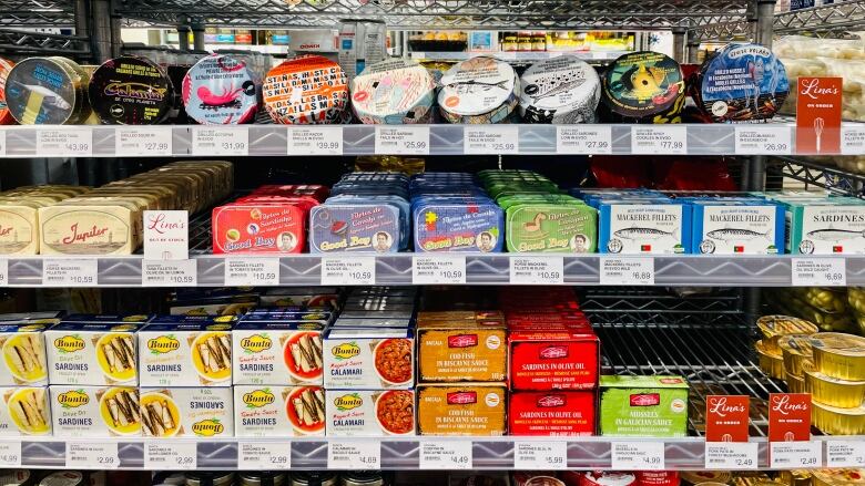 Rows of tinned fish sit on a store shelf.