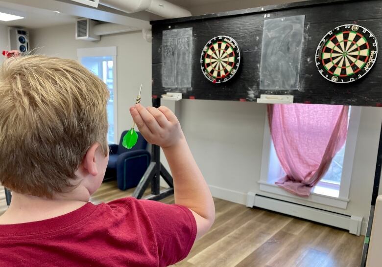 12-year-old Brody Arsenault lines up his green dart and gets ready to throw it at the board. 