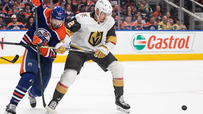 Two hockey players fight for the puck.