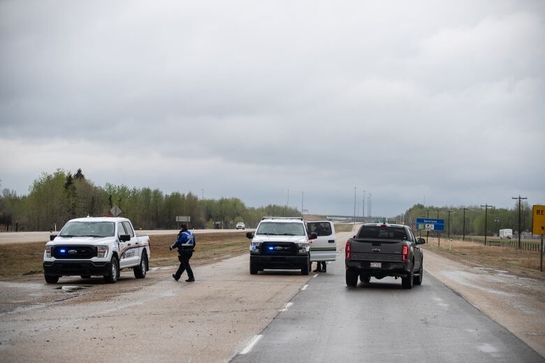 Vehicles parked blocking a roadway with a police officer 