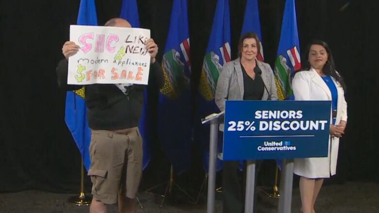 A man holds up a sign on stage at a UCP media availability.