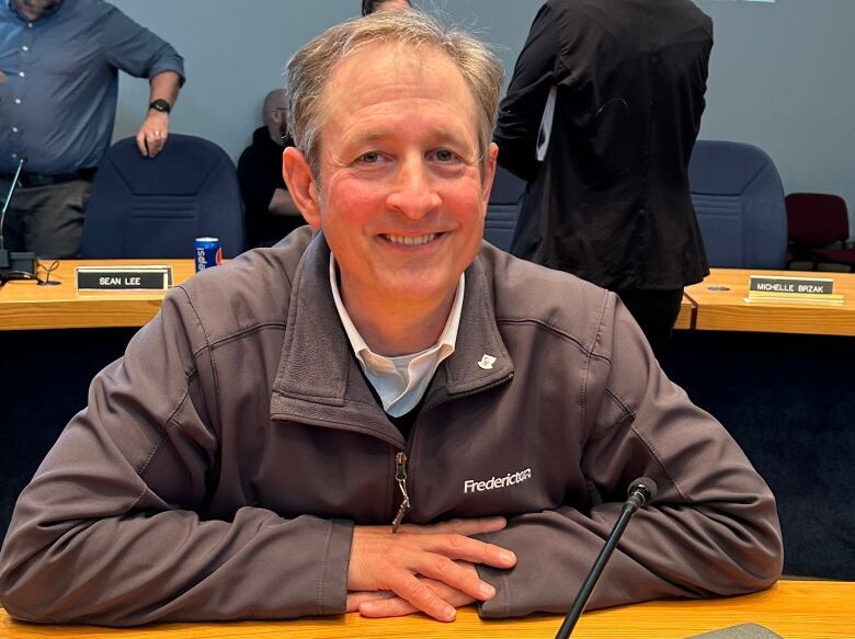 A man leaning on a wooden desk in front of him