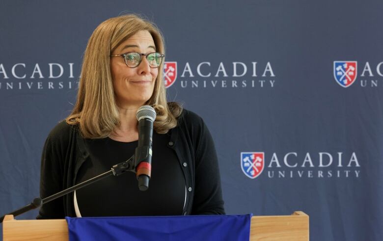 A woman stands at a podium.