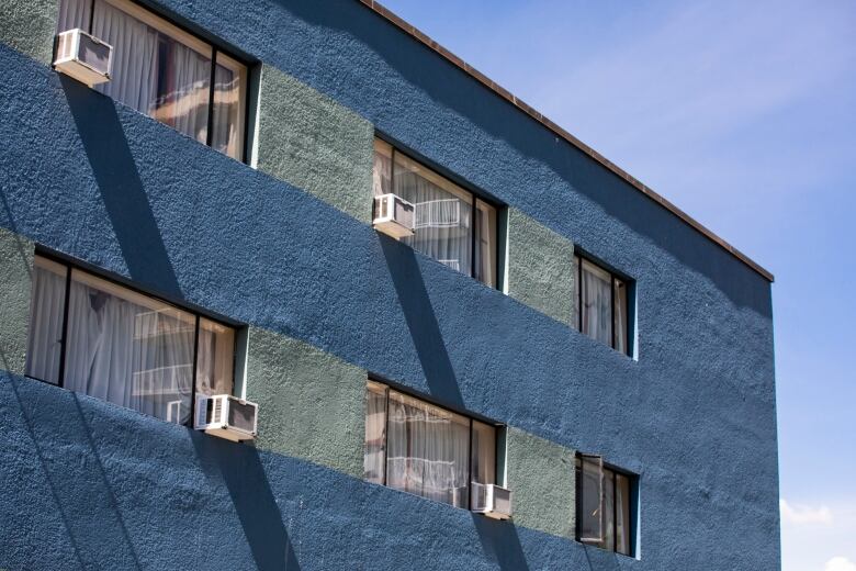 Six windows, more than half of which have air conditioners, are seen on a blue apartment building in Vancouver's West End.