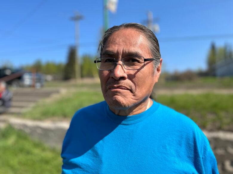 A man stands in a blue shirt with glasses