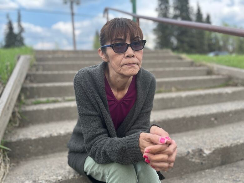 A woman in purple sits on a stoop 