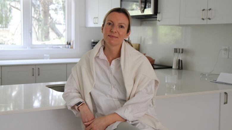 Woman sits in kitchen