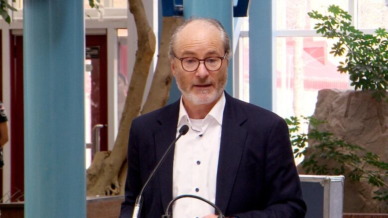 A man stands at a podium inside Portage Place shopping centre for a news conference.