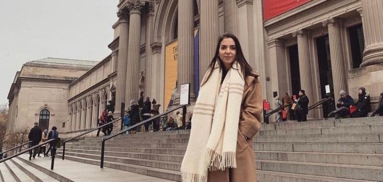 A full shot Gloria Novovic standing in front of a building.