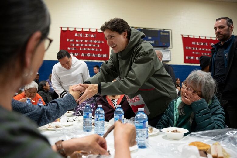 Prime Minister Justin Trudeau, centre, greets elders during a community feast in Nain, N.L. on Fri. May 12, 2023.