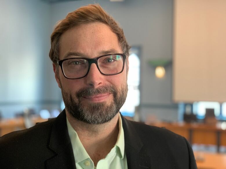 A man with glasses poses for a photo inside.