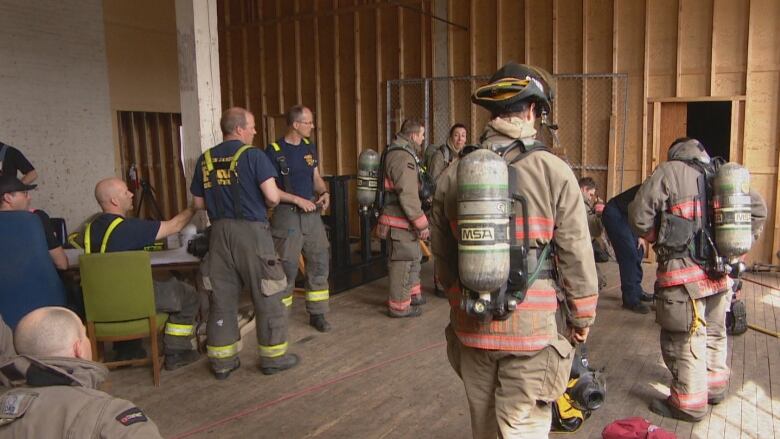 A group of firefighters in a training room stand in uniform. 