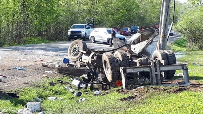 A truck lies in pieces on the side of the road.