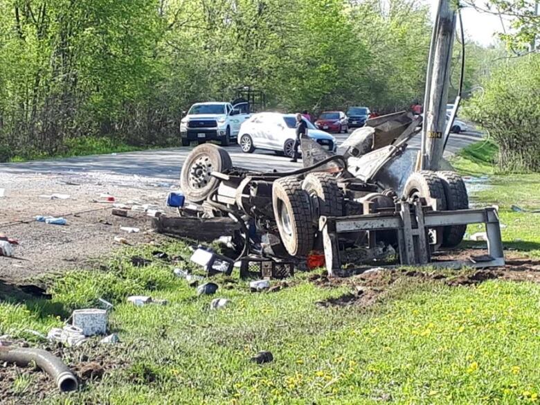 A truck lies in pieces on the side of the road.