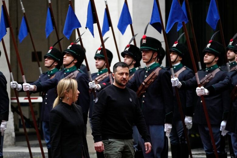 Two people walking by people with flags