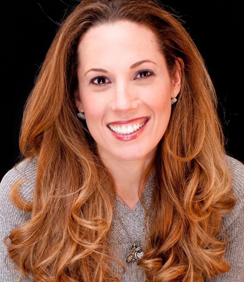 Woman in grey shirt smiles at camera