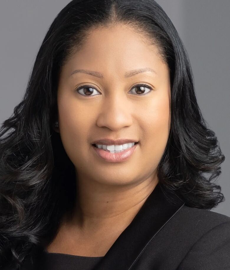 Woman in black blazer smiles at camera.