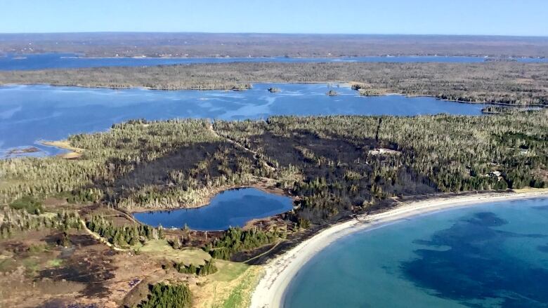 An aerial view of the fire shoes darks spots where the fire is burning, next to bodies of water.