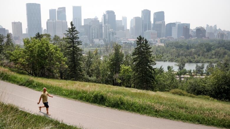 A haze of wildfire smoke from B.C. hangs over the downtown as pedestrian walks past in Calgary, Alta., Thursday, July 15, 2021