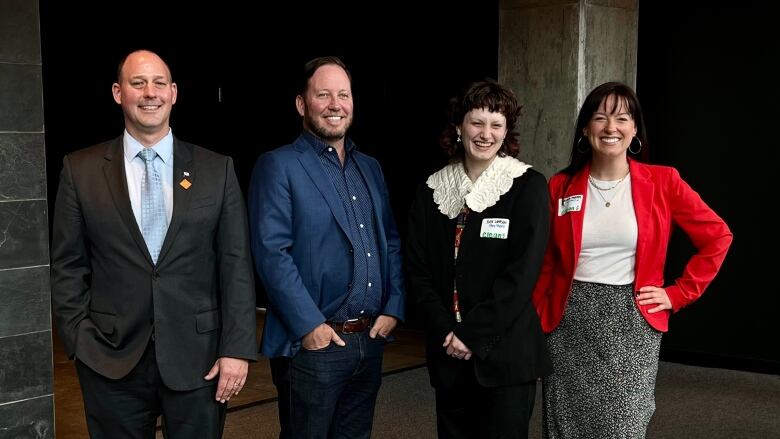 Four people are posed for a photo op after a government announcement on Monday. 