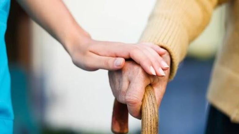 A woman places her hand on a senior's hand.