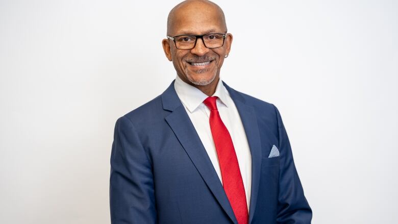 A man with glasses in a suit and tie.