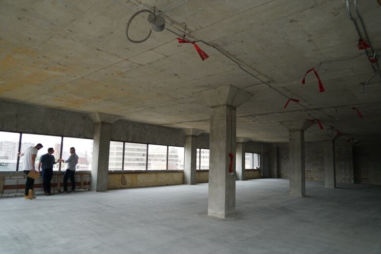 Three men talking inside a building that is undergoing renovation.