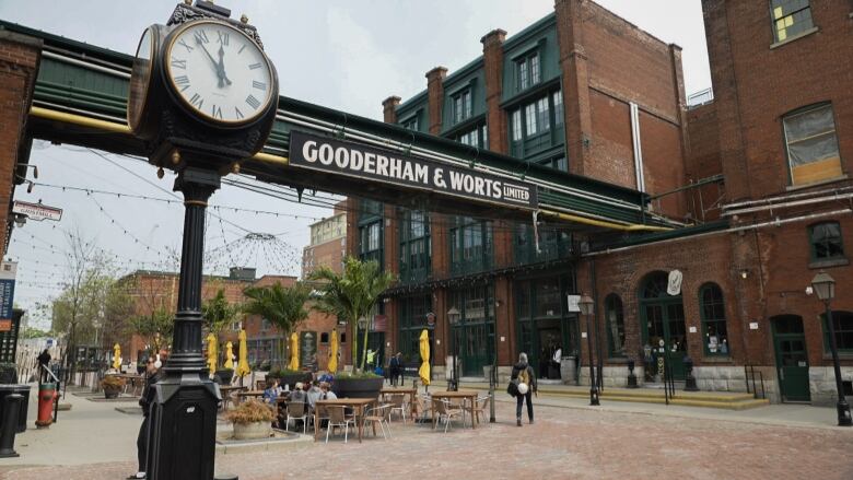 A shot of Victorian-era industrial architecture with tables and chairs in front of the buildings. 