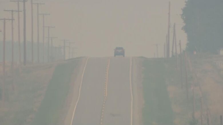 A car drives through smoke caused by wildfires burning nearby in Fort St. John, B.C.