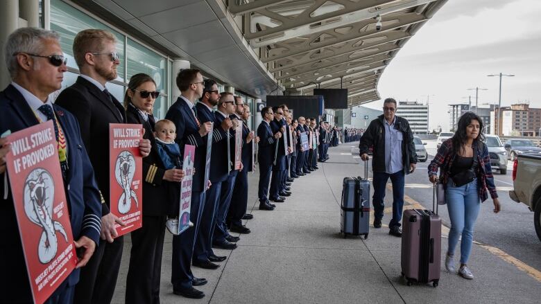 Pilots hold signs on a picket line.