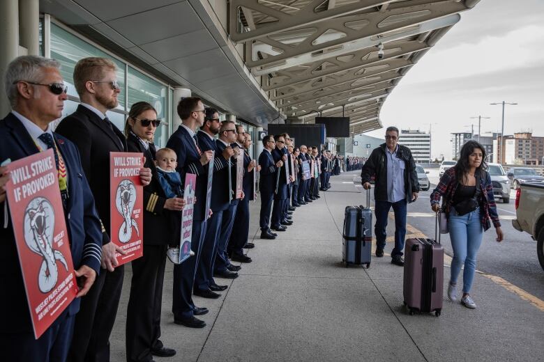 Pilots hold signs on a picket line.