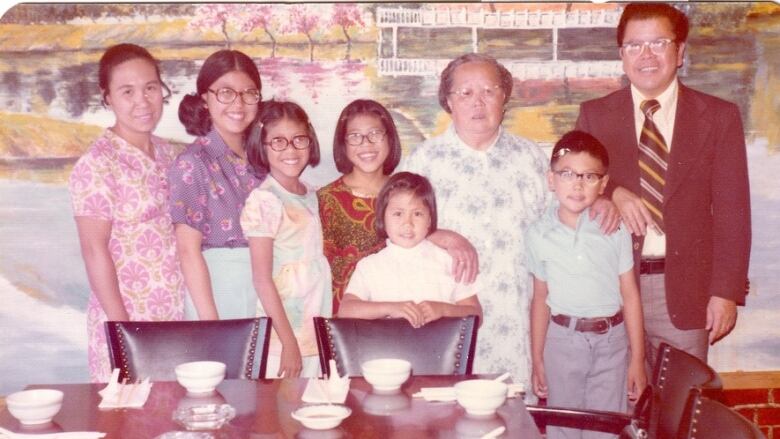 In this archival photo, a Chinese family poses around a table inside a restaurant.