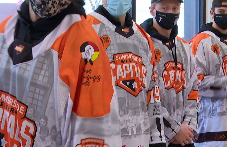 orange hockey jerseys with imagery including children from residential schools and medicine wheel