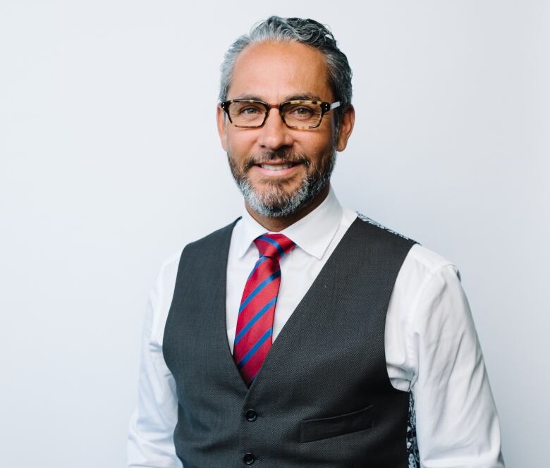 An Indigenous man wearing a suit looks at the camera and smiles.