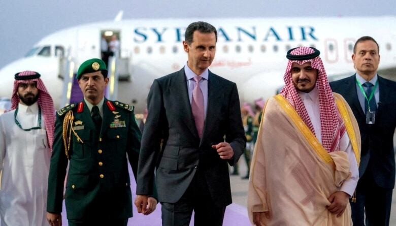 Five men walk on an airport tarmac.