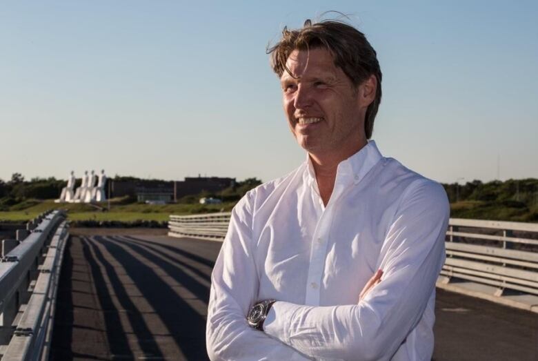 A man in a white shirt poses for a picture in a field. 