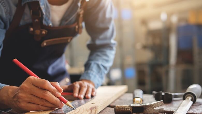 Carpenter drawing on a piece of wood in carpentry shop. 