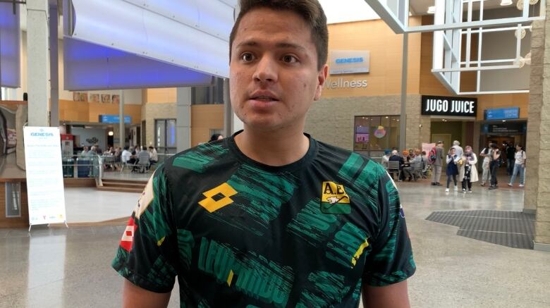 A man with a soccer shirt speaks to the camera.