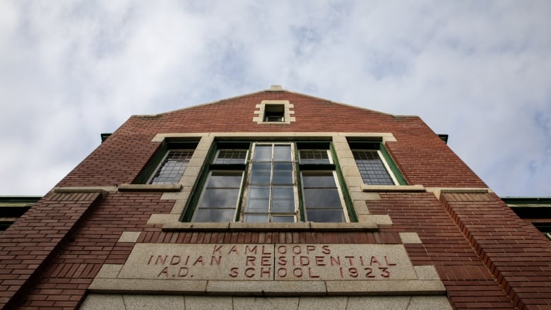 A building with a sign reads 'Kamloops Indian Residential School 1923.'