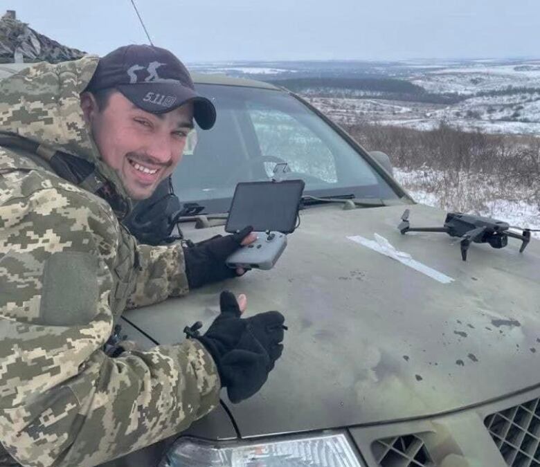 A Ukraine Armed Forces member holds a drone control and smile in a photo.