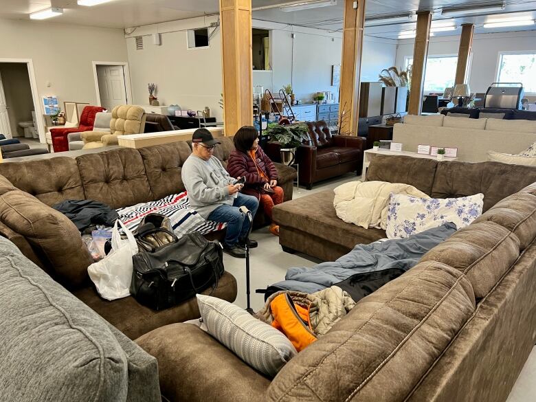 Two people on couches inside a furniture store.