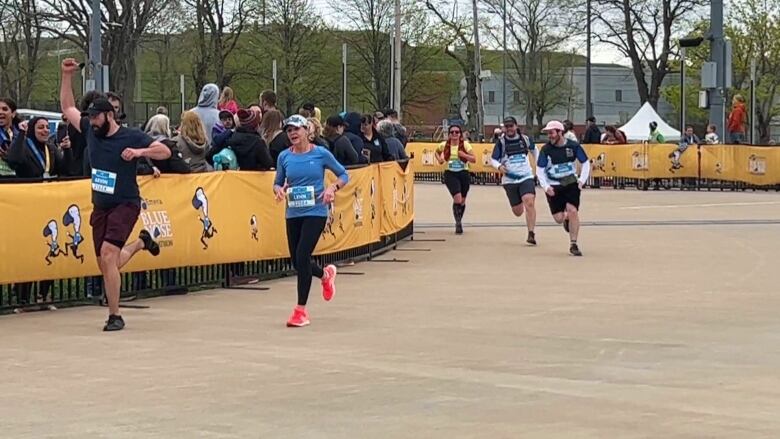 Five people are running toward the finish line. 