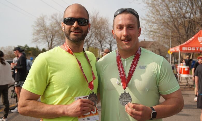 Two men stand together celebrating their crossing of the finish line for a 10 mile race. 