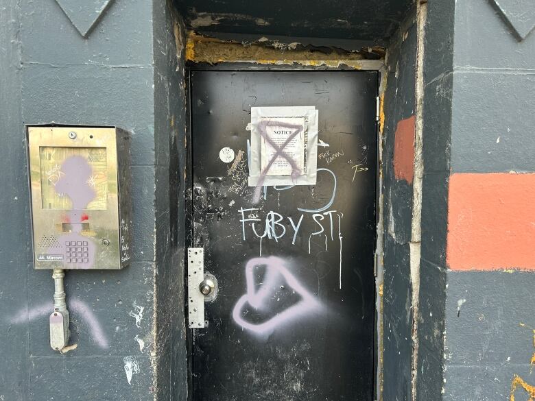 A black metal door, covered in graffiti.