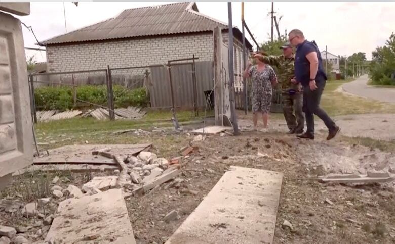 People point toward a damaged building.