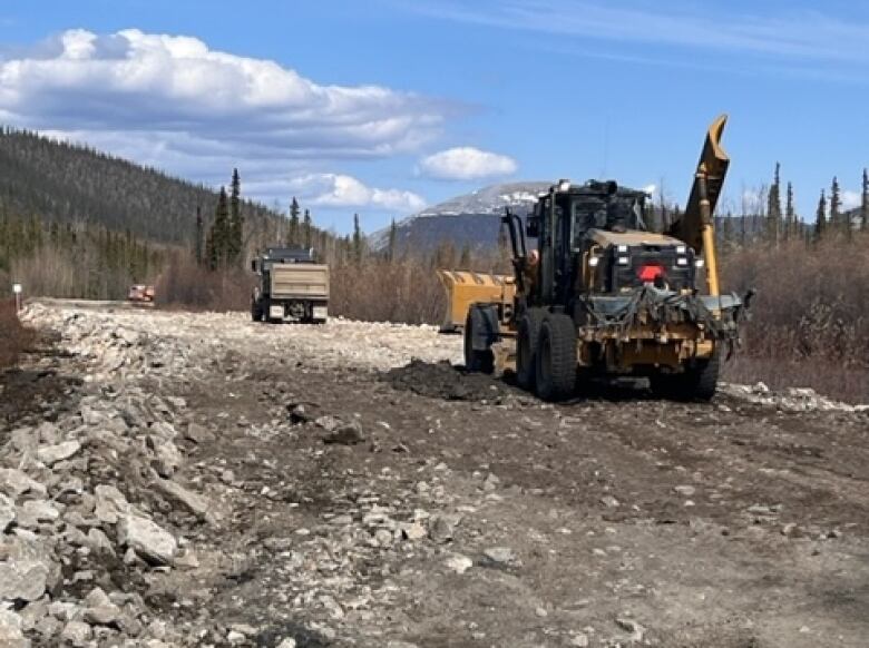 Construction machinery is seen working on a gravel road.