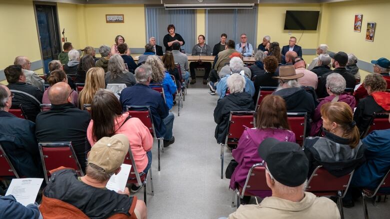 A shot from behind of a packed room of people sitting in rows.