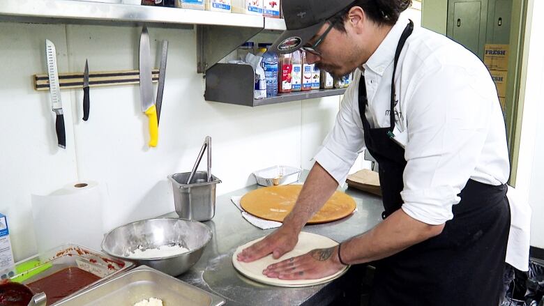 A man rolls out dough in a pan.